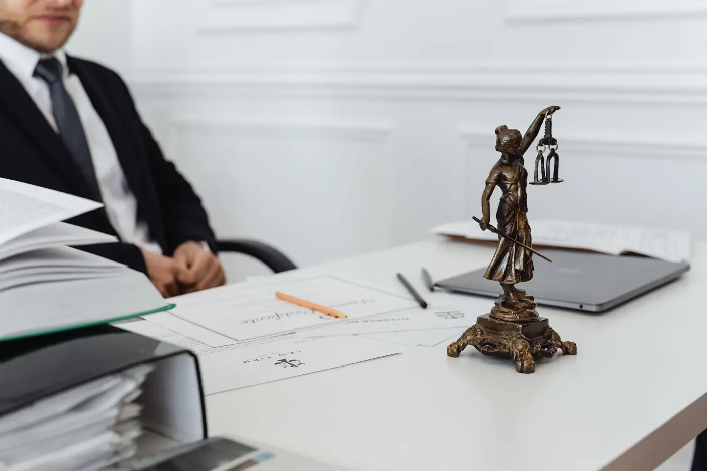 A lawyer's desk with legal files, a laptop and a Lady Justice figurine